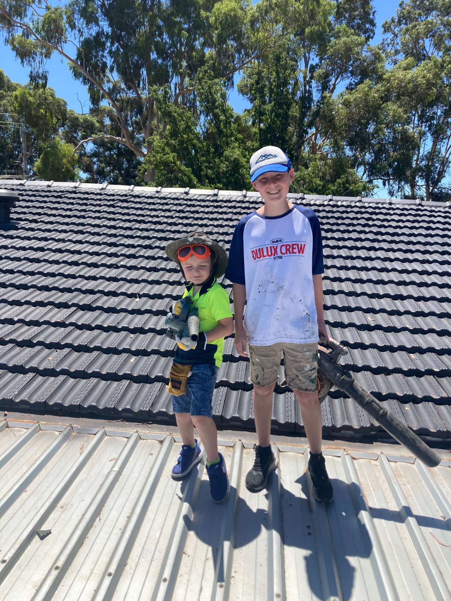 Stewart's two sons on a restored charcoal tile roof, helping out on the job